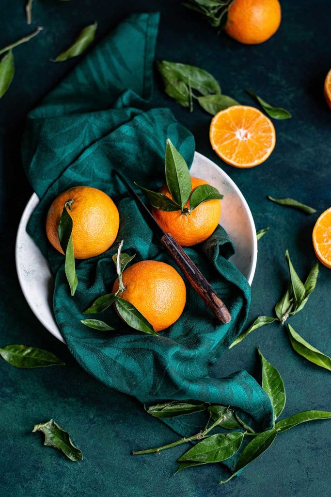 Oranges in a bowl on green background. Photo: Monika Grabkowska/Unsplash