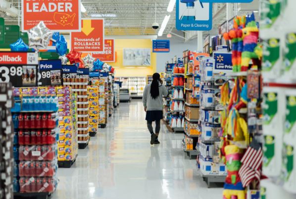 A woman walks in a supermarket aisle.